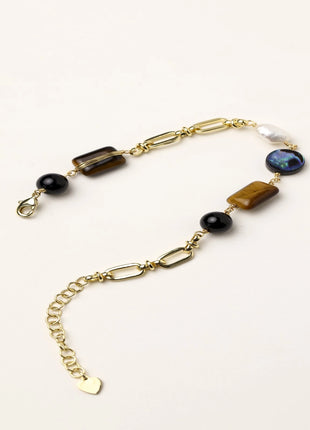 Gold-plated chain bracelet featuring tiger's eye, obsidian, freshwater pearls and abalone shell on white background