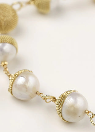 Adjustable bracelet featuring baroque pearls wrapped in gold mesh wire with delicate chain links on cream background.