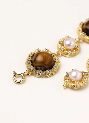 Ornate gold-plated bracelet with alternating brown tiger's eye stones and white freshwater pearls in crystal-accented settings