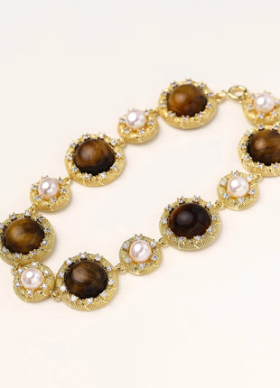 Ornate gold-plated bracelet with alternating brown tiger's eye stones and white freshwater pearls in crystal-accented settings