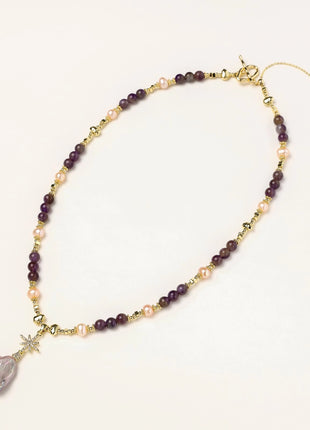 Gold-plated necklace with purple amethyst beads, pink pearls, and iridescent baroque pearl pendant beneath crystal star charm