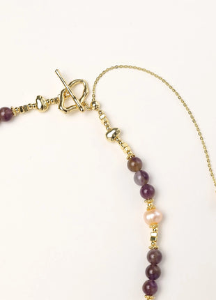 Gold-plated necklace with purple amethyst beads, pink pearls, and iridescent baroque pearl pendant beneath crystal star charm
