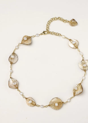 Delicate gold chain bracelet featuring iridescent shell charms with freshwater pearls on white background.
