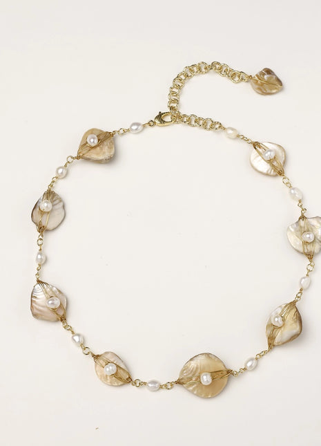 Delicate gold chain bracelet featuring iridescent shell charms with freshwater pearls on white background.
