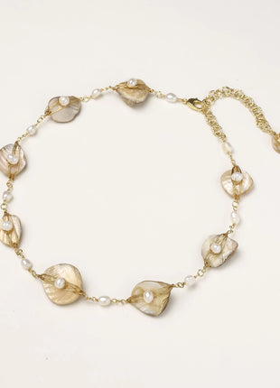 Delicate gold chain bracelet featuring iridescent shell charms with freshwater pearls on white background.
