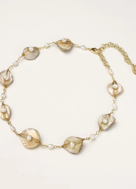Delicate gold chain bracelet featuring iridescent shell charms with freshwater pearls on white background.