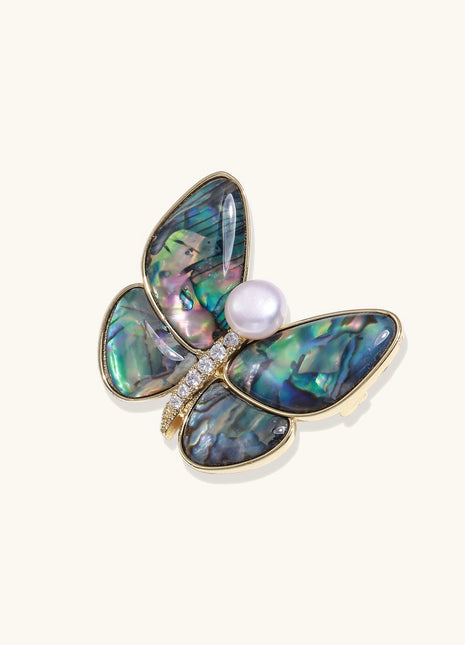 Iridescent abalone shell butterfly pin with central pearl and gold setting, showing rainbow color reflections