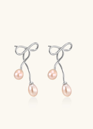 Delicate sterling silver wire earrings with organic bow shapes and two pink freshwater pearls on white background