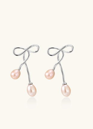 Delicate sterling silver wire earrings with organic bow shapes and two pink freshwater pearls on white background