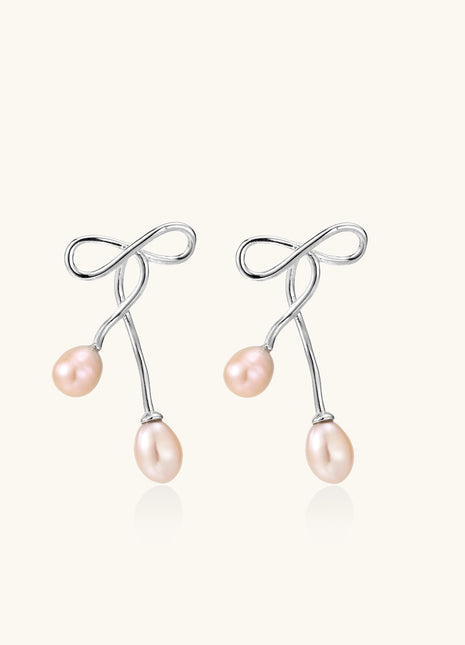 Delicate sterling silver wire earrings with organic bow shapes and two pink freshwater pearls on white background