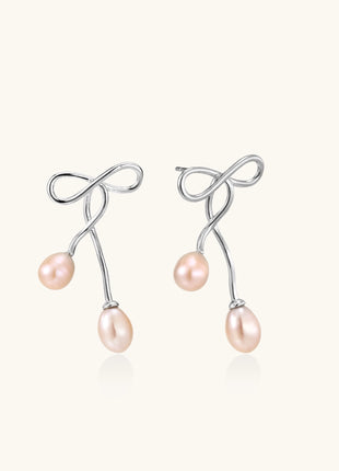Delicate sterling silver wire earrings with organic bow shapes and two pink freshwater pearls on white background
