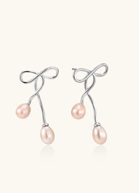 Delicate sterling silver wire earrings with organic bow shapes and two pink freshwater pearls on white background