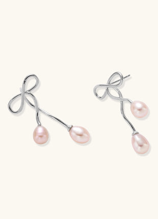 Delicate sterling silver wire earrings with organic bow shapes and two pink freshwater pearls on white background