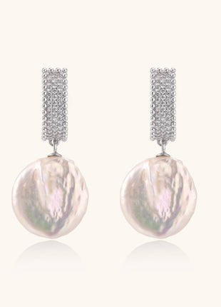 Sterling silver huggie earrings with lustrous baroque pearls displaying iridescent pink and cream tones on white background.