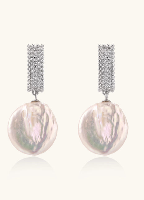 Sterling silver huggie earrings with lustrous baroque pearls displaying iridescent pink and cream tones on white background.