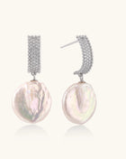 Sterling silver huggie earrings with lustrous baroque pearls displaying iridescent pink and cream tones on white background.