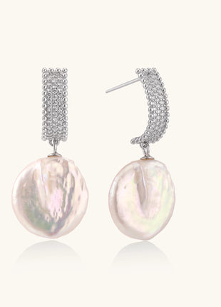 Sterling silver huggie earrings with lustrous baroque pearls displaying iridescent pink and cream tones on white background.