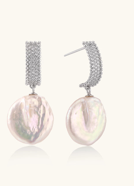 Sterling silver huggie earrings with lustrous baroque pearls displaying iridescent pink and cream tones on white background.