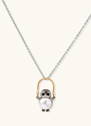 Silver owl pendant holding a round freshwater pearl on an adjustable chain against white background