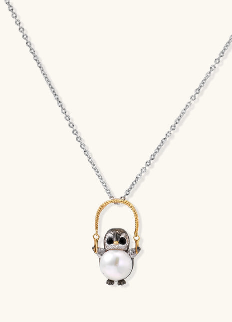 Silver owl pendant holding a round freshwater pearl on an adjustable chain against white background