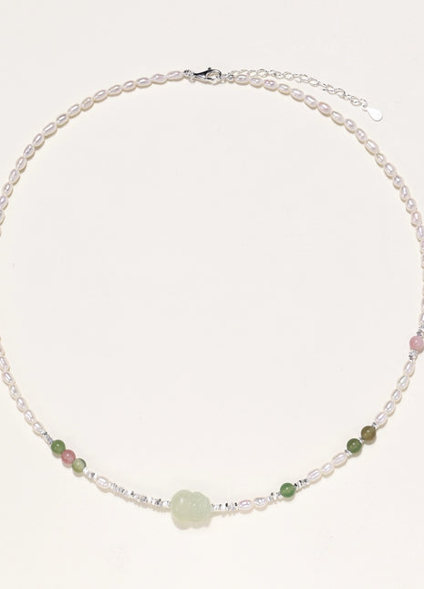Delicate sterling silver necklace with freshwater pearls, green serpentine centerpiece, and mixed agate beads on white background.