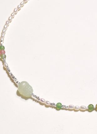Delicate sterling silver necklace with freshwater pearls, green serpentine centerpiece, and mixed agate beads on white background.