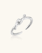 Delicate sterling silver ring with geometric knot design on white background, showcasing adjustable open band.