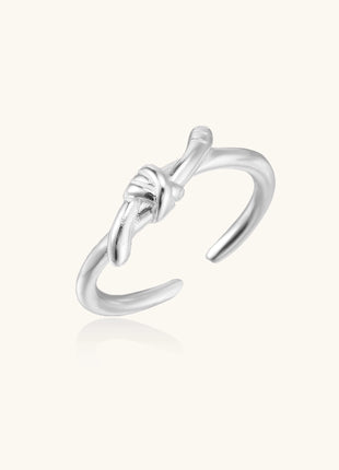 Delicate sterling silver ring with geometric knot design on white background, showcasing adjustable open band.