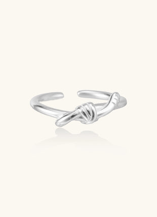Delicate sterling silver ring with geometric knot design on white background, showcasing adjustable open band.