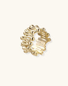 Close-up of chunky 18K gold-plated brass ring with flowing wave-like sculptural design on neutral background.
