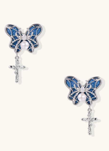 Ornate gold-plated butterfly earrings with blue enamel wings, white pearl centers, and silver cross dangles