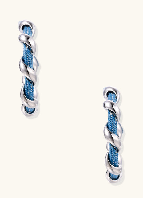 Twisted hoop earrings featuring blue denim fabric braided with gold-plated metal in a spiral design on white background.