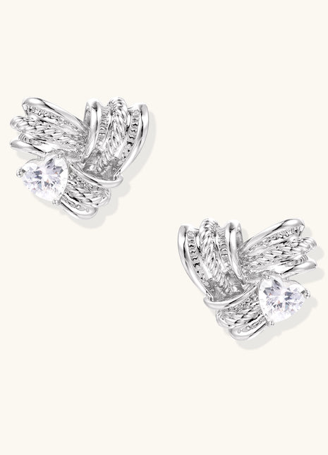 Gold-plated brass stud earrings with intricate twisted knot design and sparkling zirconia stones on neutral background.