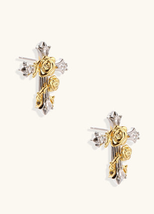 Two-tone cross earrings with gold roses and silver base featuring crystal accents on beige background.