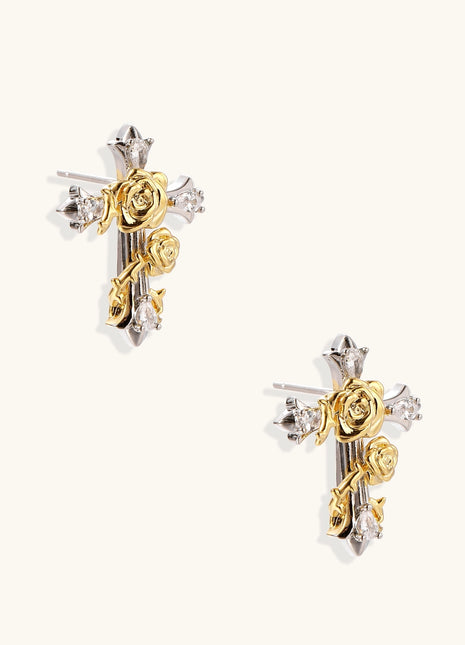 Two-tone cross earrings with gold roses and silver base featuring crystal accents on beige background.