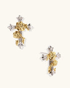 Two-tone cross earrings with gold roses and silver base featuring crystal accents on beige background.