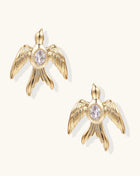 Pair of gold-plated eagle stud earrings with spread wings and purple zirconia center stones on white background.