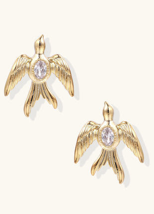 Pair of gold-plated eagle stud earrings with spread wings and purple zirconia center stones on white background.