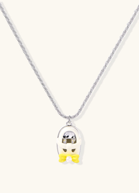Minimalist gold plated brass necklace with cute capsule pendant featuring yellow bow detail on neutral background.