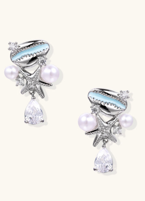 Gold-plated dangle earrings with enamel shell charms, white pearls, starfish accents, and crystal drops on white background.