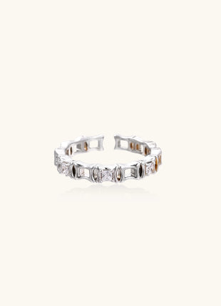 Close-up of geometric gold-plated ring with alternating rectangular blocks and zirconia crystals on white background.