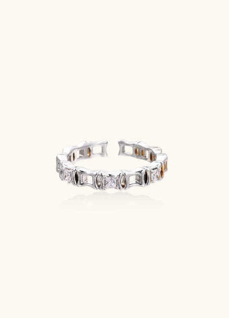Close-up of geometric gold-plated ring with alternating rectangular blocks and zirconia crystals on white background.