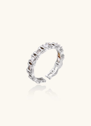 Close-up of geometric gold-plated ring with alternating rectangular blocks and zirconia crystals on white background.