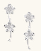 Gold-plated floral dangle earrings with zirconia crystal centers and curved stems on white background.
