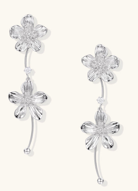 Gold-plated floral dangle earrings with zirconia crystal centers and curved stems on white background.