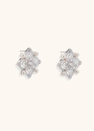 Detailed view of sterling silver stud earrings with geometric filigree design and small freshwater pearls on white background.