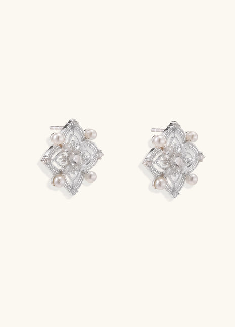 Detailed view of sterling silver stud earrings with geometric filigree design and small freshwater pearls on white background.