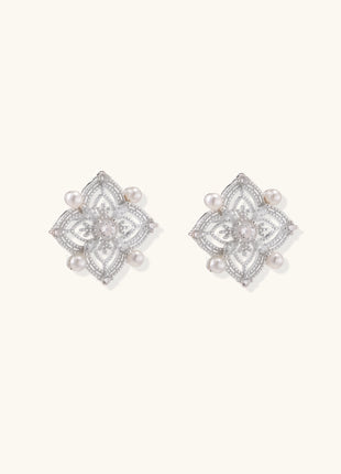 Detailed view of sterling silver stud earrings with geometric filigree design and small freshwater pearls on white background.