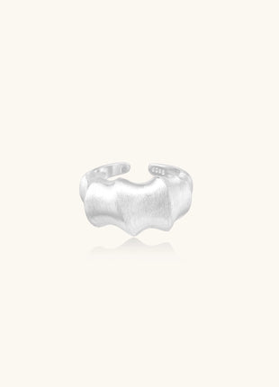 Chunky sterling silver ring with organic flowing design and brushed matte finish on neutral background