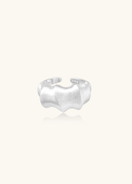 Chunky sterling silver ring with organic flowing design and brushed matte finish on neutral background